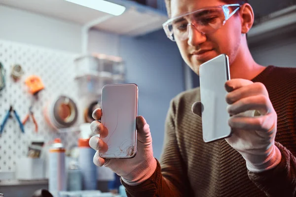 Technician holds two identical smartphones for comparison, in one hand broken and in another new — Stock Photo, Image