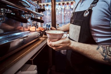 Bir kafede aromatik bir cappuccino bir bardağı tutan Barista