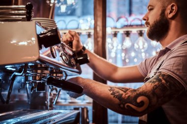 Dövmeli barista şık sakal ve saç modeli bir kafe ya da Restoran bir kahve makinesinde çalışma ile