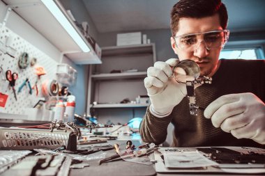 Bir büyüteç kullanarak tablet çip elektronik teknisyeni tamir kırık tablet dikkatle inceliyor