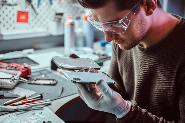 Technicien détient deux smartphones identiques pour la comparaison, dans une main cassée et dans un autre nouveau — Photo