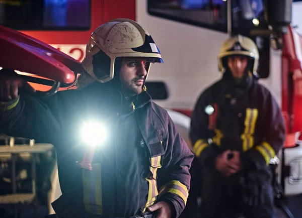 두 소방 관 화재 트럭 옆에 보호 유니폼 서 입고. 밤 시간에 전화에 도착 — 스톡 사진