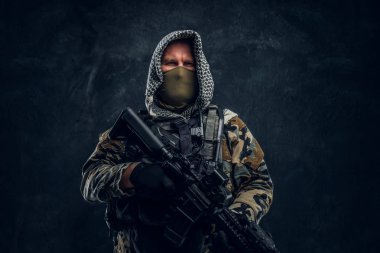 Special forces soldier in military uniform wearing mask and hood holding an assault rifle. clipart