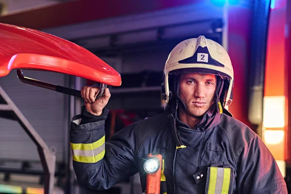 Portret przystojny strażak noszenie ochronnej jednolite z latarką zawarte, stojąc w garażu remizy — Zdjęcie stockowe