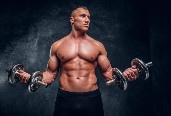 Muscular young guy trains with two dumbbells. — Stock Photo, Image