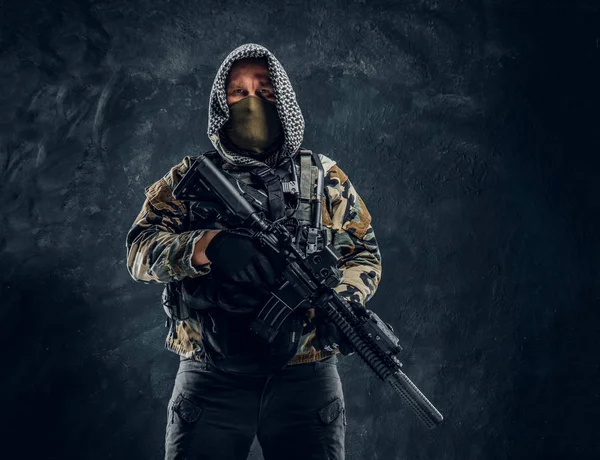 Soldado de las fuerzas especiales en uniforme militar con máscara y capucha sosteniendo un rifle de asalto . — Foto de Stock
