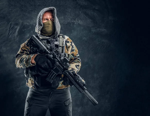 Soldat al forţelor speciale în uniformă militară purtând mască şi capotă ţinând o puşcă de asalt . — Fotografie, imagine de stoc