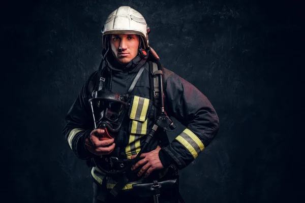 Pompier en équipement de protection complet tenant un masque à oxygène et regardant une caméra . — Photo