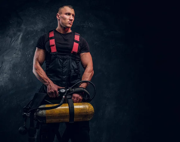 Retrato de un bombero sosteniendo un tanque de oxígeno y mirando hacia los lados . —  Fotos de Stock