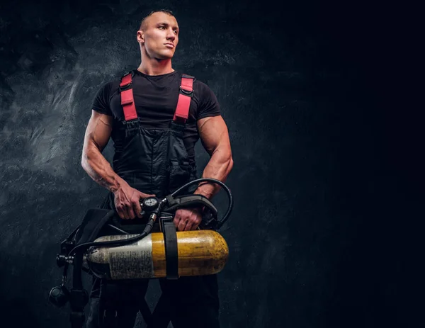 Retrato de un bombero sosteniendo un tanque de oxígeno y mirando hacia los lados . —  Fotos de Stock