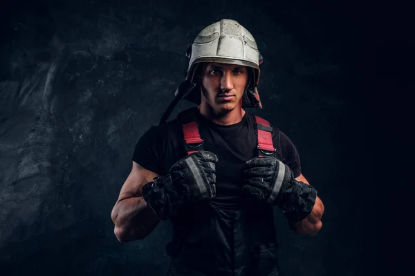 Portrait of a handsome man wearing a fire helmet and gloves, looking at a camera — Stock Photo, Image