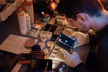 Teknisyen dikkatle smartphone içinde modern bir tamirciye iç unsurları bütünlüğünü inceler