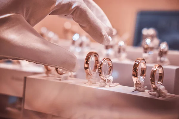 Mano en guantes lleva a anillos exclusivos en la vitrina de una joyería — Foto de Stock