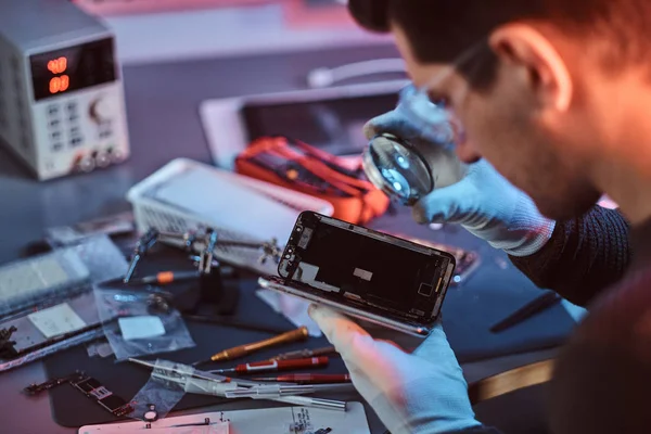 Técnico examina cuidadosamente a integridade dos elementos internos do smartphone em uma oficina de reparação moderna — Fotografia de Stock
