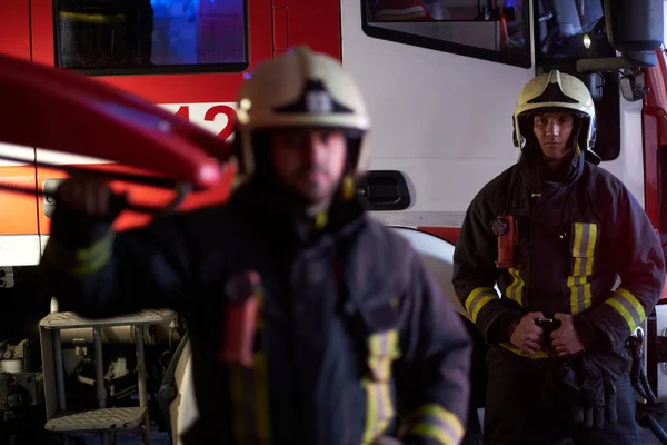 두 용감한 소방 관 화재 트럭 옆에 보호 유니폼 서 입고. 밤 시간에 전화에 도착 — 스톡 사진