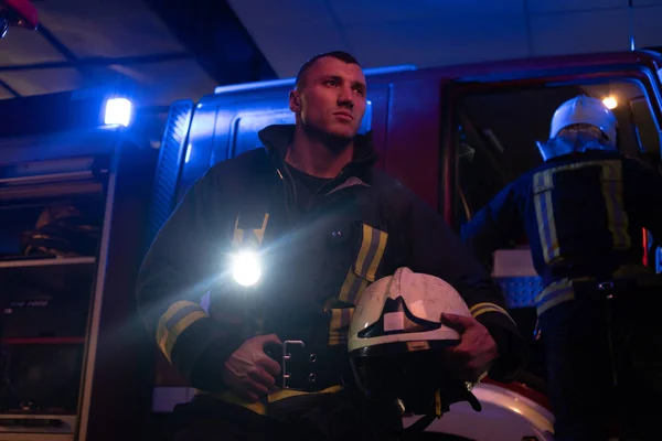 Los bomberos vinieron a la llamada por la noche. Bombero guapo con un uniforme protector con una linterna incluida — Foto de Stock