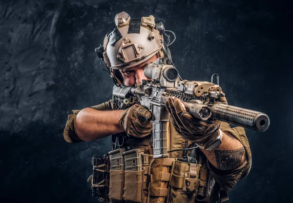 Elite unit, special forces soldier in camouflage uniform holding an assault rifle with a laser sight and aims at the target. — Stock Photo, Image