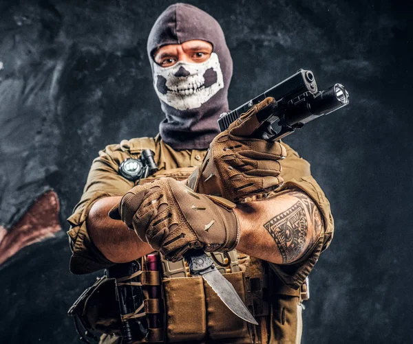 Bir terörist askeri üniforma ve bir tabanca ve bir bıçak ve tehditkar bir bakışla bakar, kamera tutan bir kafatası yün — Stok fotoğraf