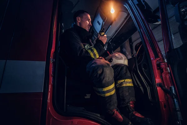 Die Feuerwehr rückte noch in der Nacht an. Feuerwehrmann sitzt im Feuerwehrauto und spricht im Radio — Stockfoto