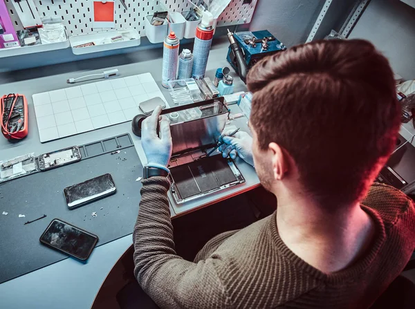 O técnico repara um computador tablet quebrado em uma oficina de reparo — Fotografia de Stock