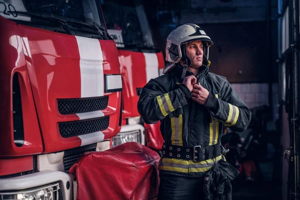 Ochranné oděvy Fireman uniformy stojící vedle hasičské v garáži — Stock fotografie