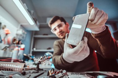 Kırık bir gövdeye sahip bir smartphone bir tamirciye gösterilen elektronik teknisyeni