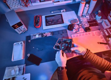Bir tamirci üstten görünüm görüntüsünü smartphone içinde modern bir tamirciye iç parçalarını dikkatle incelemek için Büyüteç kullanır. Kırmızı ve Mavi ışıklı aydınlatma