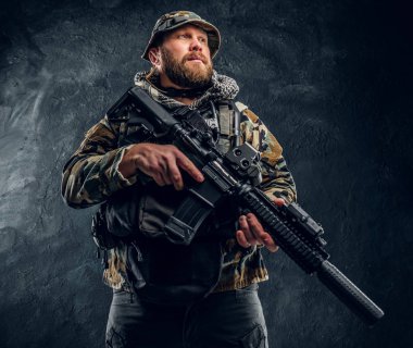 Özel Kuvvetler asker bir saldırı tüfeği tutan askeri kamuflaj üniformalı. Studio fotoğraf bir karanlık dokulu duvara