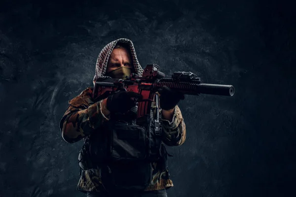 Voják speciálních sil ve vojenské uniformě, na sobě masku a kapuce drží útočná puška s laserovým zaměřovačem a cíle na cíl. — Stock fotografie