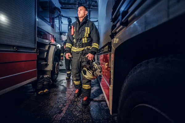 화재 부서의 차고에 있는 2 개의 소방차 사이 산책 보호 유니폼 두 용감한 소방 관의 전체 길이 초상화 — 스톡 사진