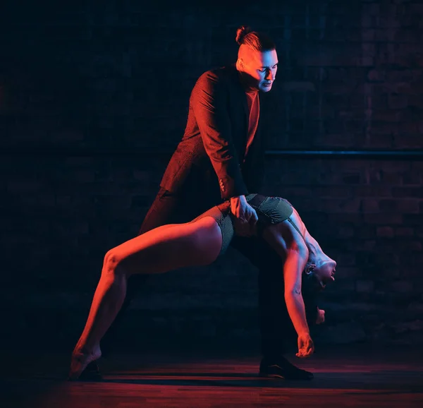Belo casal dançando na pista de dança em um clube noturno. Dançarinos se apresentando no escuro com iluminação — Fotografia de Stock