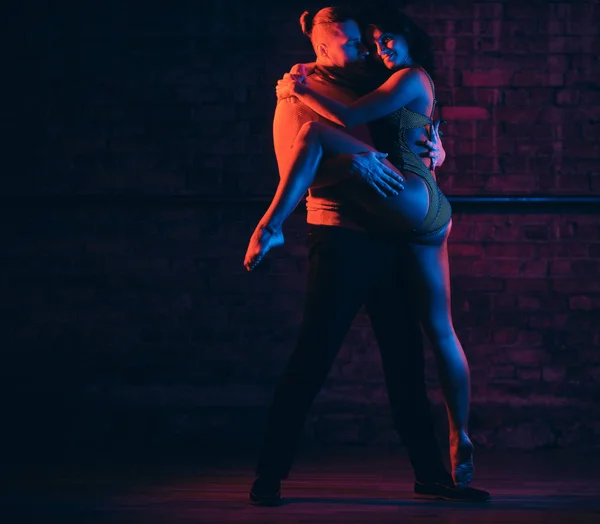 Beautiful couple dancing on the dance floor in a night club. Dancers performing in the dark with illumination