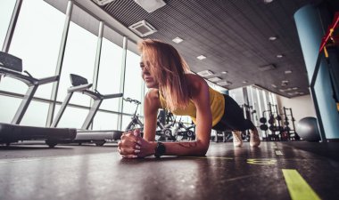 Modern spor salonunda, çalışma ince fitness kadının tahta bir mat yapması