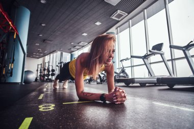 Modern spor salonunda, çalışma ince fitness kadının tahta bir mat yapması