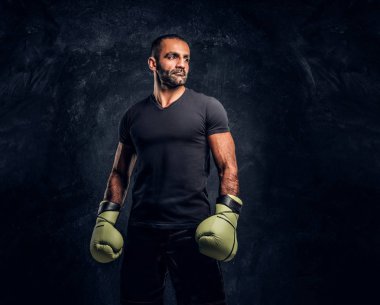 Siyah bir gömlek ve eldiven acımasız bir profesyonel avcı portresi. Studio fotoğraf bir karanlık dokulu duvara