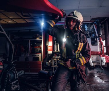 Koruyucu el feneri ile üniforma giyen bir itfaiyeci itfaiye garajda çalışma dahil