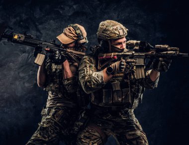 İki Özel Kuvvetler asker tam koruyucu ekipman saldırı tüfeği tutan ve hedefleri hedef. Studio fotoğraf bir karanlık dokulu duvara.