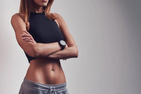 Mujer fitness segura usando ropa deportiva posando con los brazos cruzados . — Foto de Stock