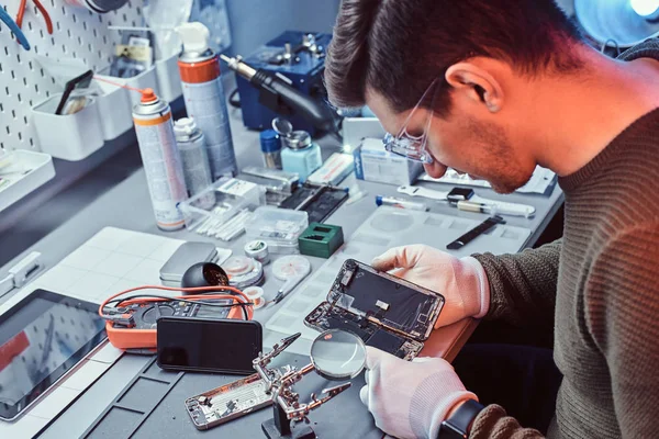 Técnico examina cuidadosamente la integridad de los elementos internos del teléfono inteligente en un taller de reparación moderno —  Fotos de Stock