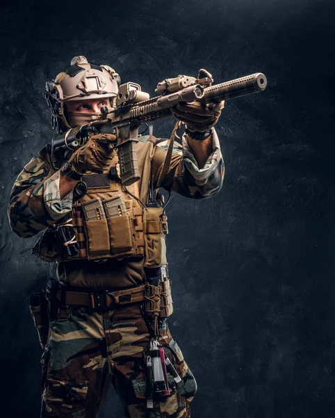 Unidad de élite, soldado de las fuerzas especiales en uniforme de camuflaje sosteniendo un rifle de asalto con una mira láser y apunta al objetivo . — Foto de Stock