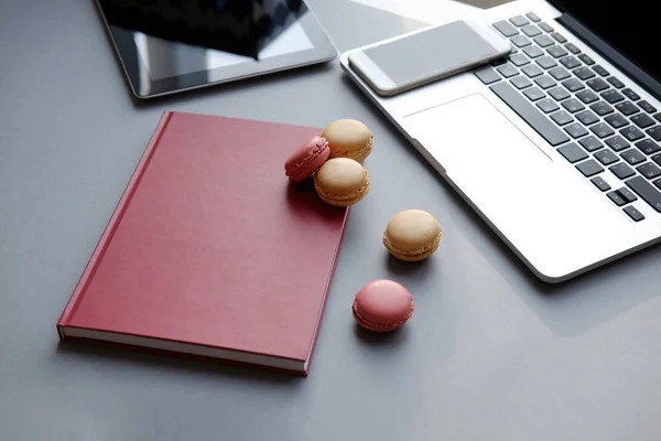 Laptop, tablet, smartphone, notebook and colorful French macaron on a table. Work, lunch, office — Stock Photo, Image