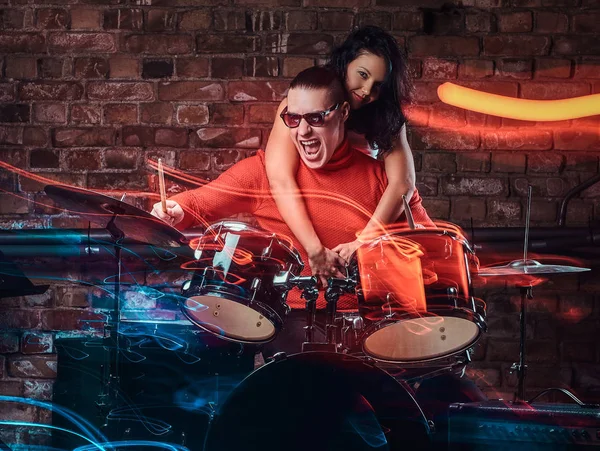 Ragazza abbraccia il suo idolo che suona su un tamburo set in discoteca contro un muro di mattoni — Foto Stock