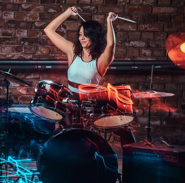 Молодая девушка-музыкант играет на барабанах и тарелках. Живая музыка в ночном клубе

