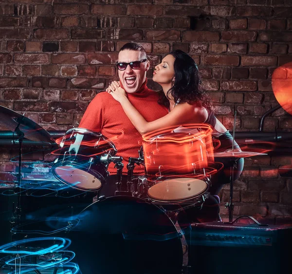 Girl hugs her idol who plays on a drum set in nightclub against a brick wall — Stock Photo, Image