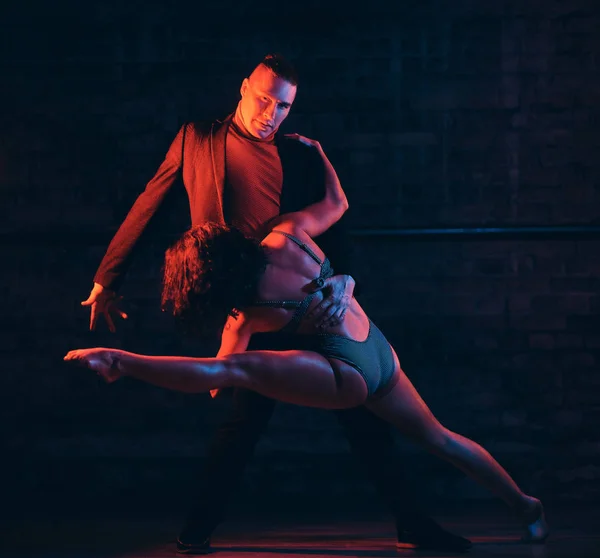 Belo casal dançando na pista de dança em um clube noturno. Dançarinos se apresentando no escuro com iluminação — Fotografia de Stock