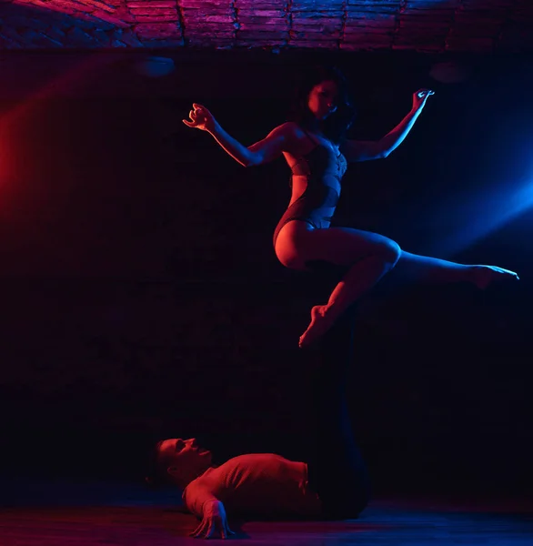 Beautiful couple dancing on the dance floor in a night club. Dancers performing in the dark with illumination