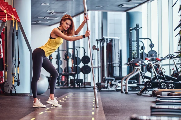 Fitnessmädchen posiert im modernen Fitnessstudio auf einer Langhantel für eine Kamera — Stockfoto