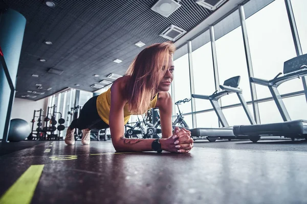 Modern spor salonunda, çalışma ince fitness kadının tahta bir mat yapması — Stok fotoğraf