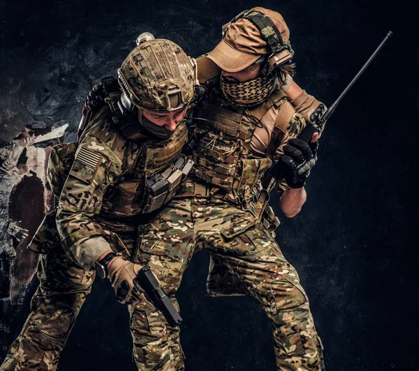 Kampfkonflikte, besondere Mission. der Soldat, der Teamkollegen aus dem Schlachtfeld trägt. Studiofoto vor dunkler Wand — Stockfoto