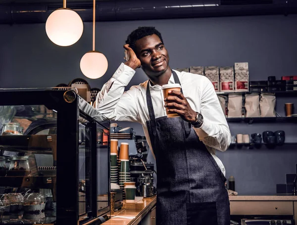 Bir fincan kahve ile bir kafede bir sayaçta yaslanmış ve yana doğru seyir süre tutarak Afrika barista